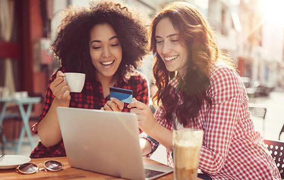 Friends using a credit card shopping online at a cafe.