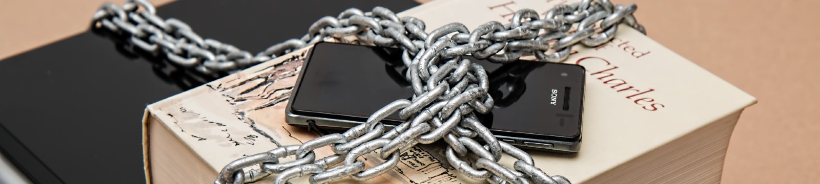 Stock photo of books and cell phone locked down with chains.