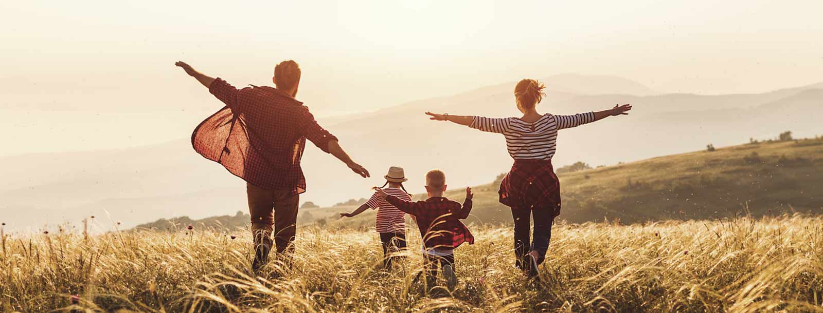 Family walking through a field at sunset.