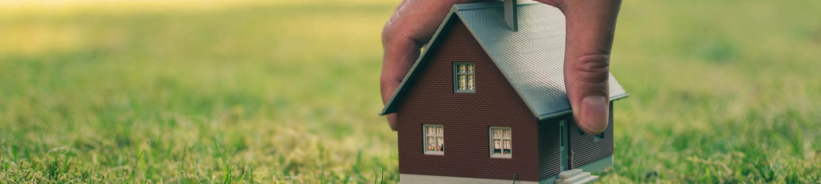 Hand holding a house model.